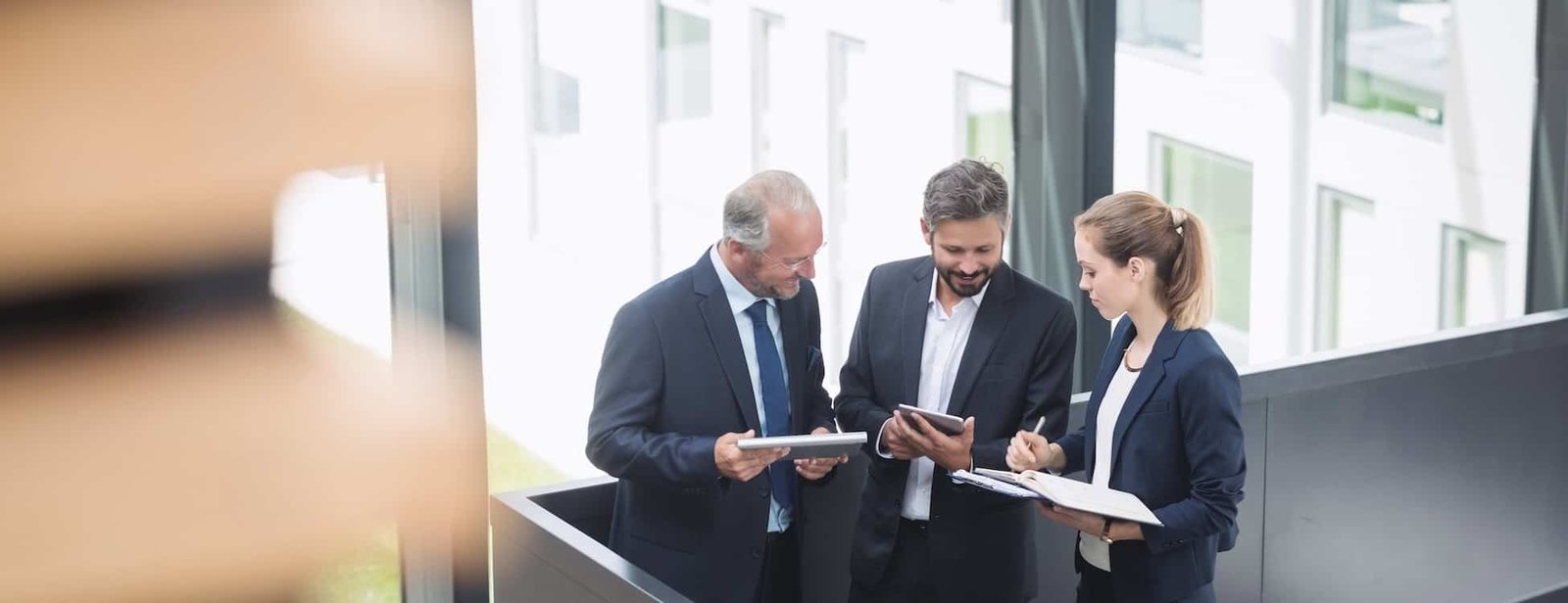 business professionals discussing digital marketing strategies using tablets and notebooks in a modern office environment, representing local SEO and AI search optimization services